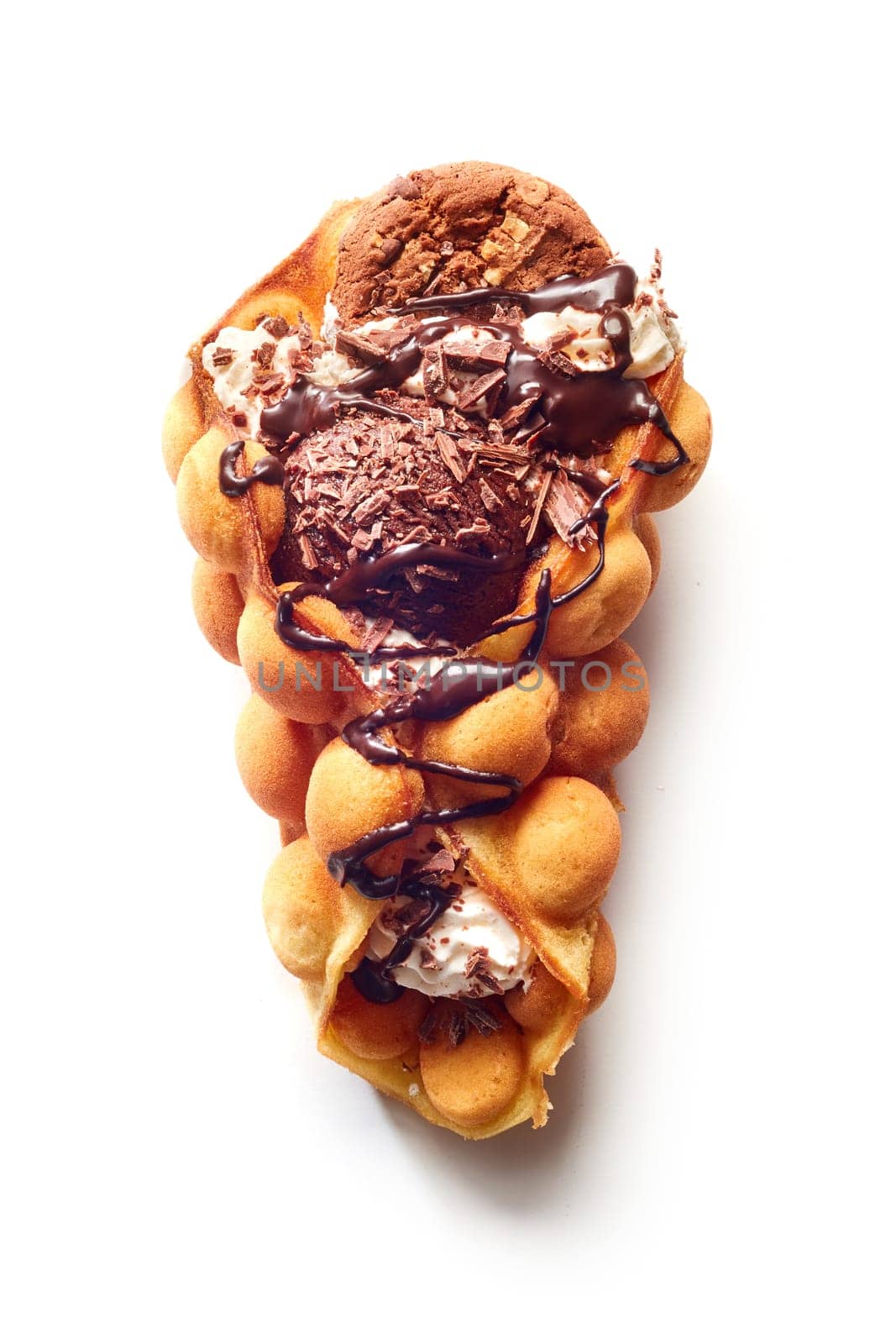 Top view of egg waffle cone with ice cream and chocolate with cookie and syrup on white surface