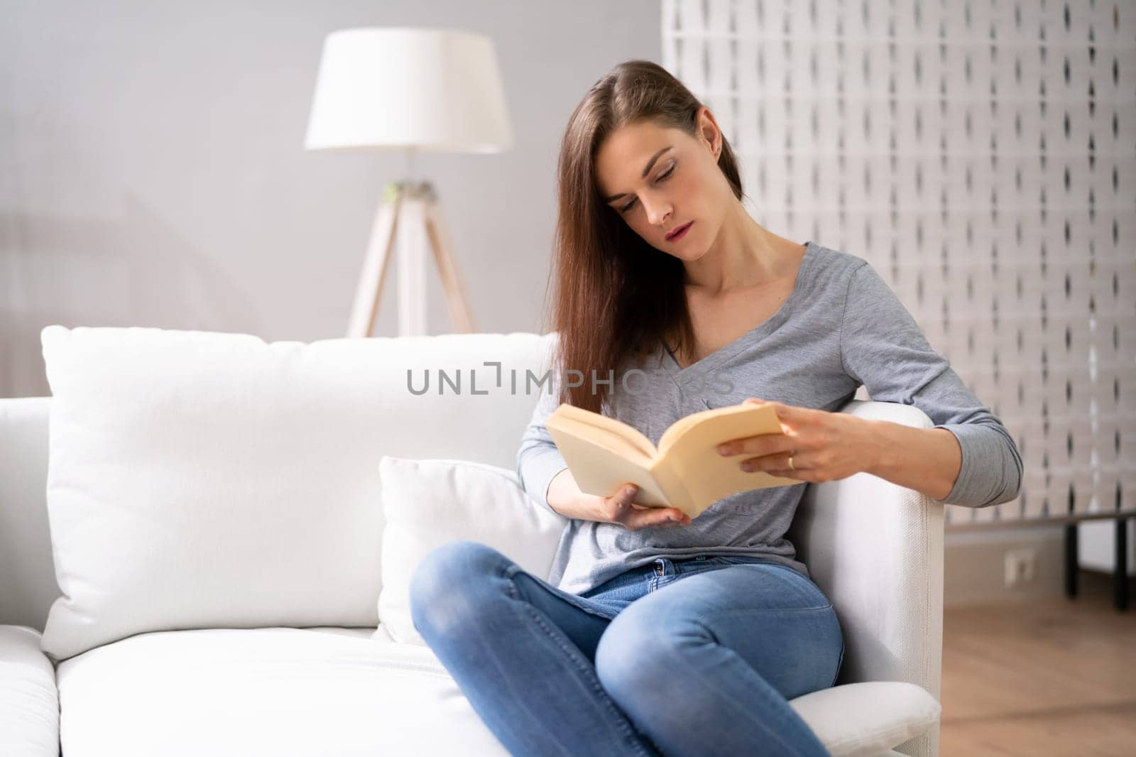 Adult Person Sitting On Sofa Reading Book. Relaxation Lifestyle