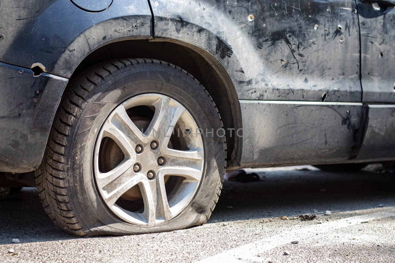 Shot car during the war in Ukraine. A car of civilians with shrapnel holes from explosions. Car accident. Car graveyard. Traces of shots on the body. The vehicle was damaged after the shelling