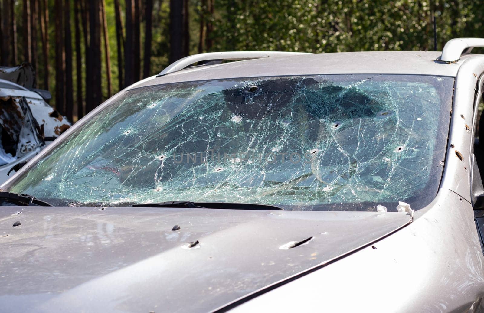 Holes on the windshield of the car, it was shot from a firearm. Bullet holes. Smash car windshield, broken and damaged car. The bullet made a cracked hole in the glass