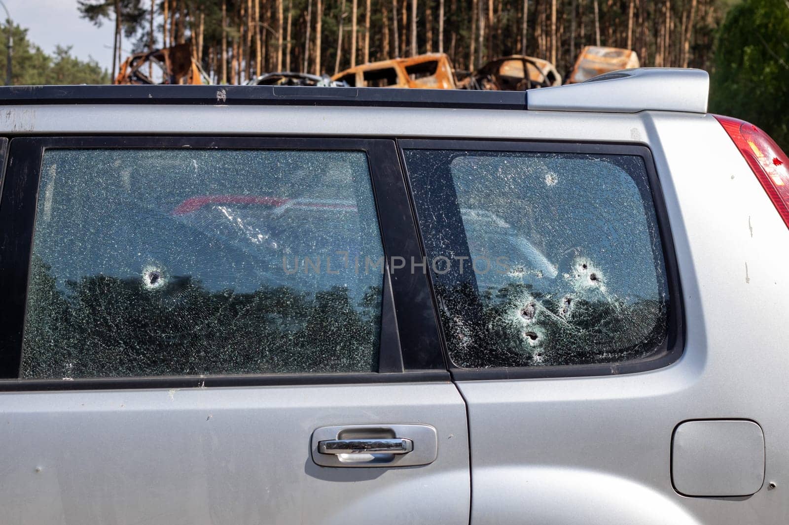 Traces of shots on the body of the car. War between Russia and Ukraine. Part of a civilian car that was fired upon during the evacuation of unarmed people from the combat zone