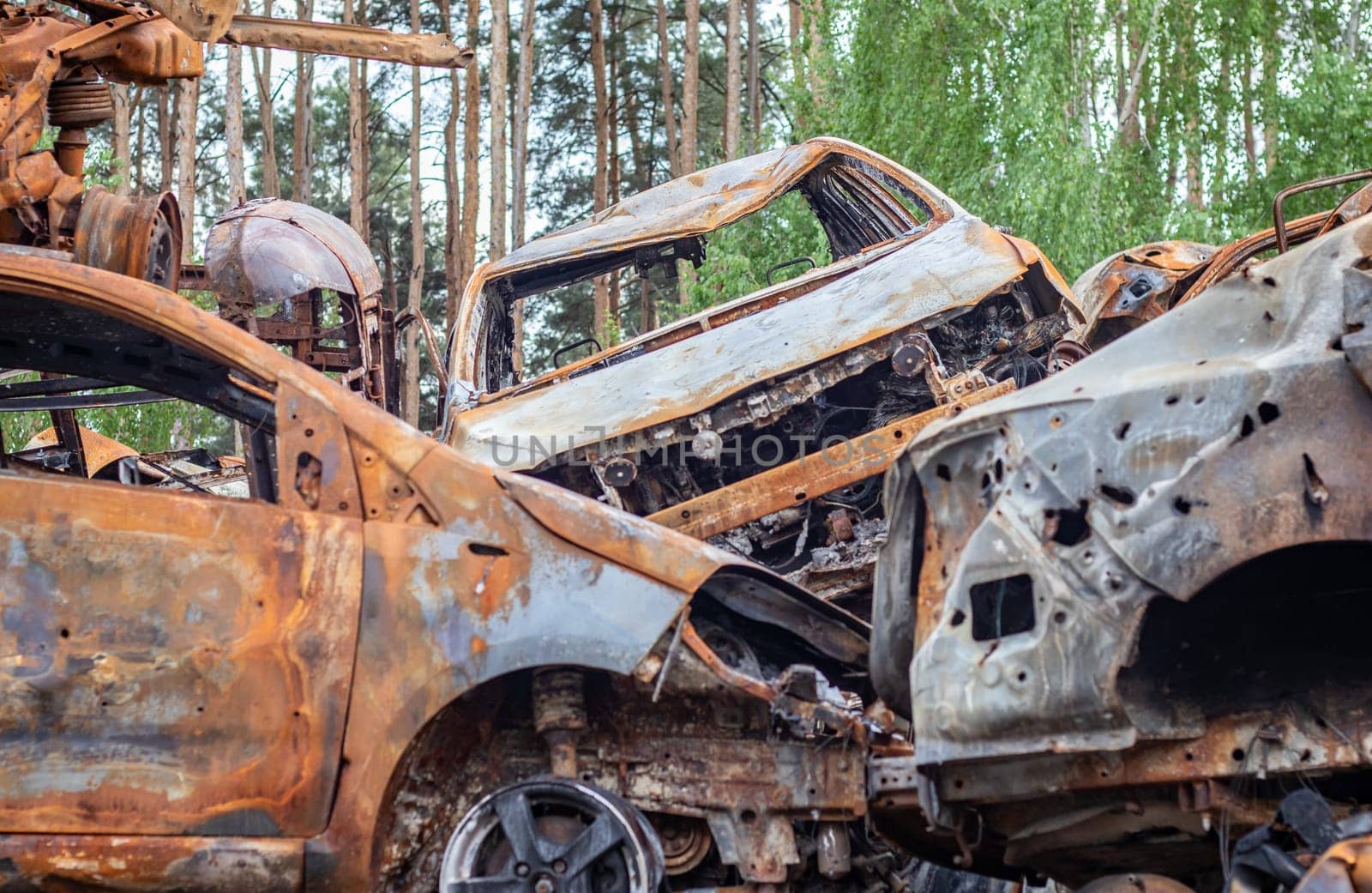 A view of burnt-out cars after rocket attacks by the Russian military. War of Russia against Ukraine. Civil vehicle after the fire. Cemetery of cars in the city of Irpin. Rusty pile of metal