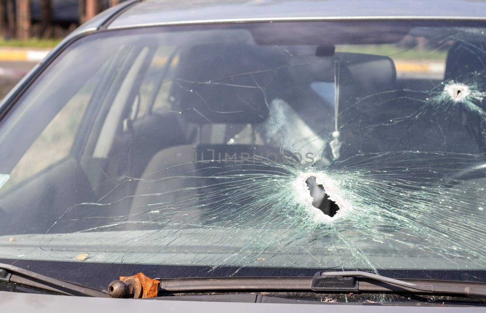 Holes on the windshield of the car, it was shot from a firearm. Bullet holes. Smash car windshield, broken and damaged car. The bullet made a cracked hole in the glass
