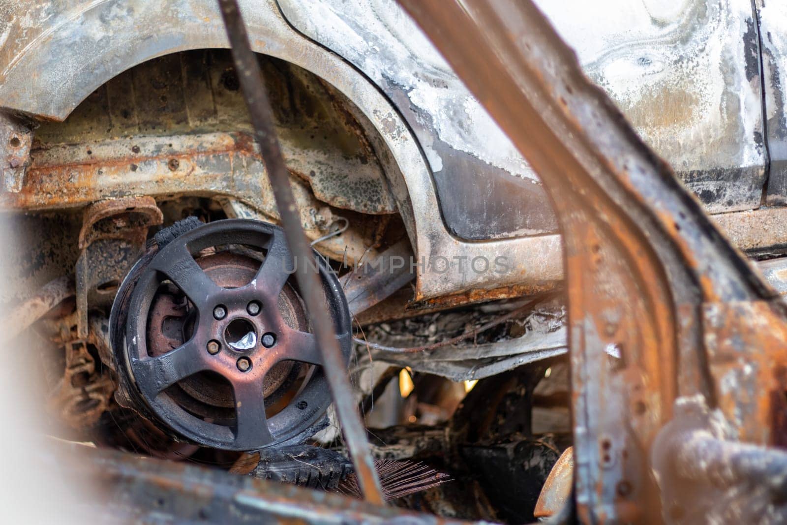 Cars after the fire. Iron parts of a burnt car. Burnt-out cars abandoned on the side of a quiet countryside. Explosion, the result of a fire. Car insurance concept. War of Russia against Ukraine