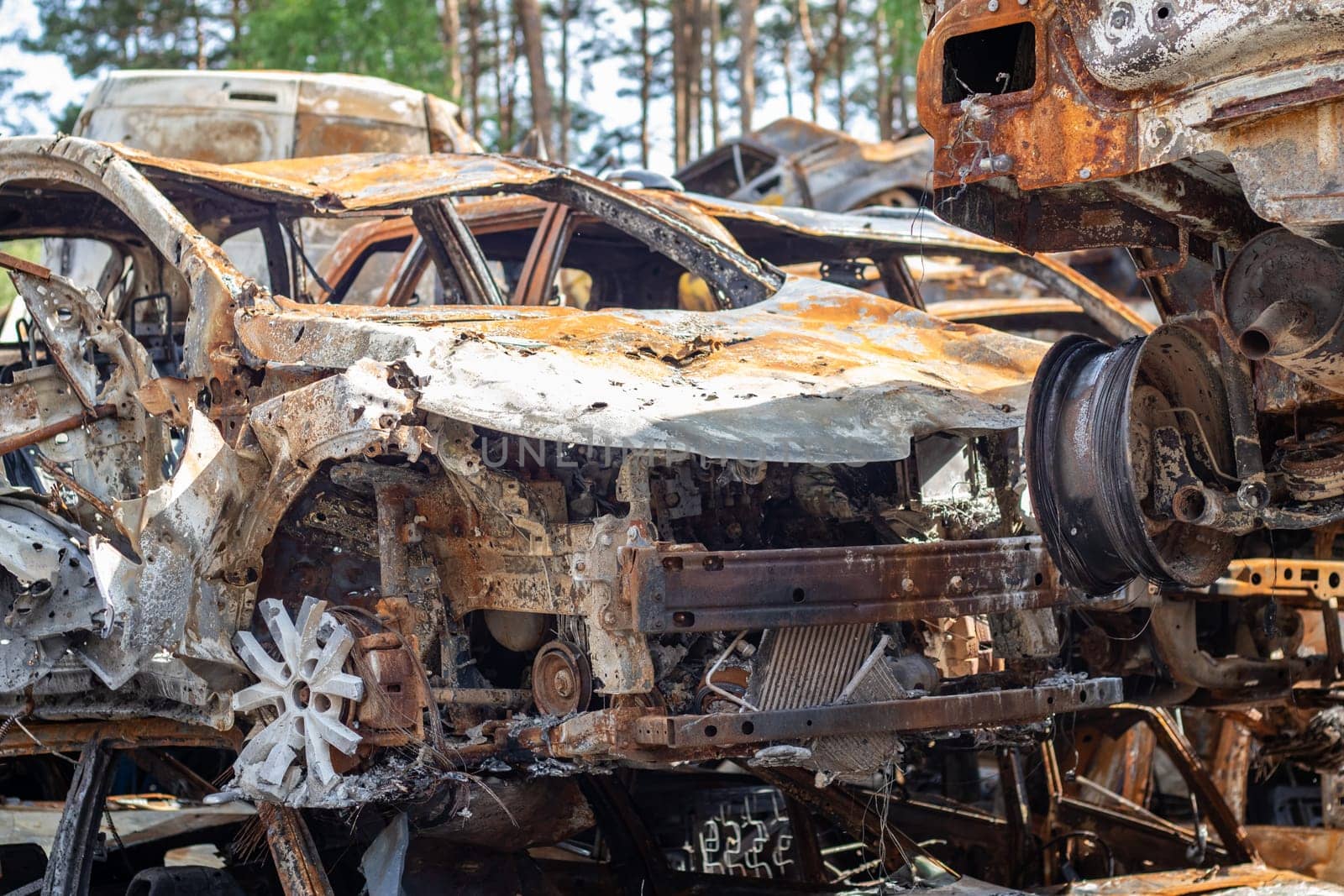 Cars after the fire. Iron parts of a burnt car. Burnt-out cars abandoned on the side of a quiet countryside. Explosion, the result of a fire. Car insurance concept. War of Russia against Ukraine