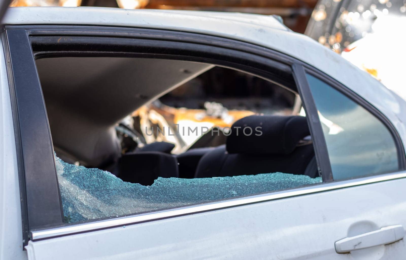 Criminal incident. Breaking into a car parked on the street. Broken side glass and the passenger compartment behind it. A crime committed by a thief, stealing things. Car after an accident