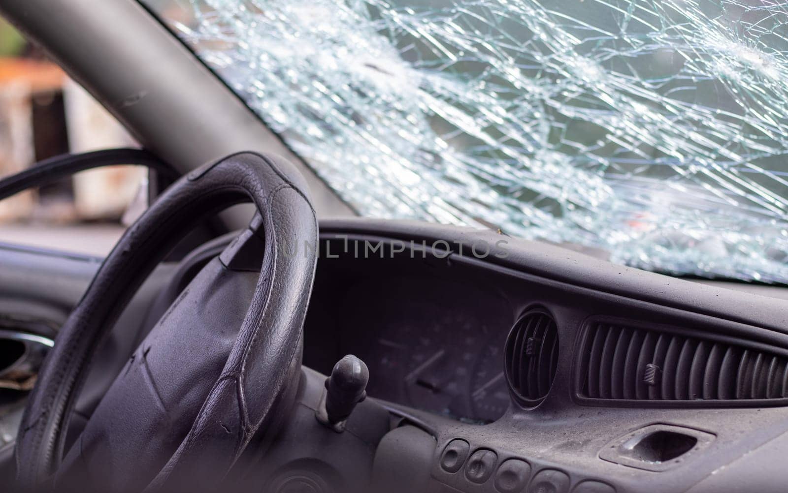 Close-up of the steering wheel of a car after an accident. The driver's airbags did not deploy. Soft focus. Broken windshield with steering wheel. Vehicle interior. Black dashboard and steering wheel