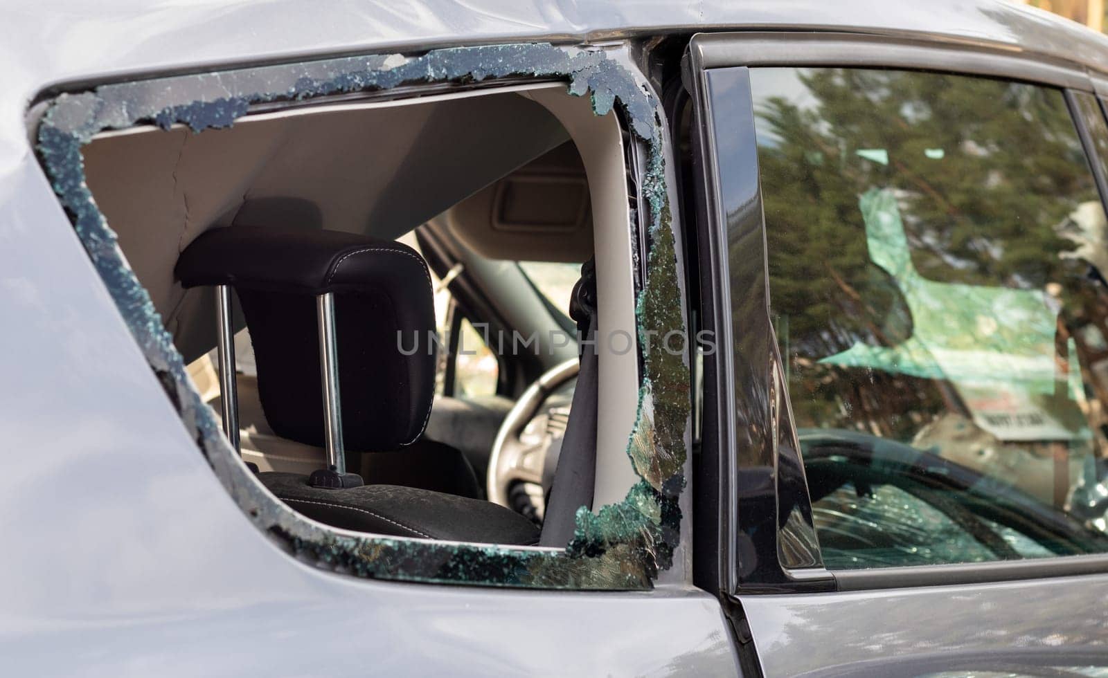 Criminal incident. Breaking into a car parked on the street. Broken side glass and the passenger compartment behind it. A crime committed by a thief, stealing things. Car after an accident