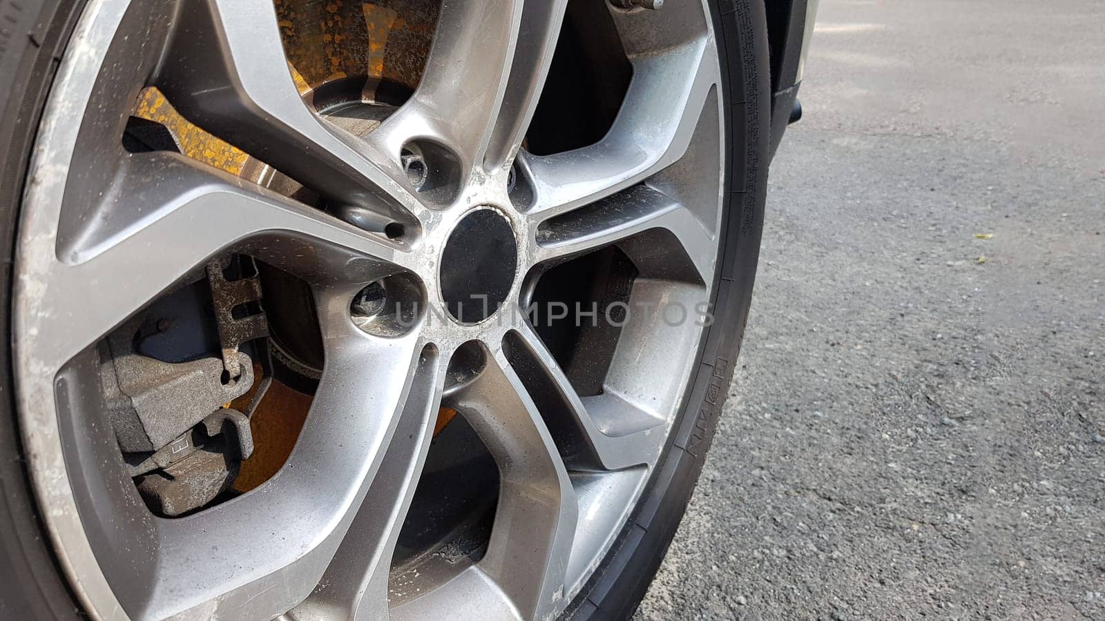 The original alloy wheel, dirty and scratched on the car close-up. Worn car wheels are waiting for repair. selective focus. Car repair and restoration concept required. Damaged car wheel