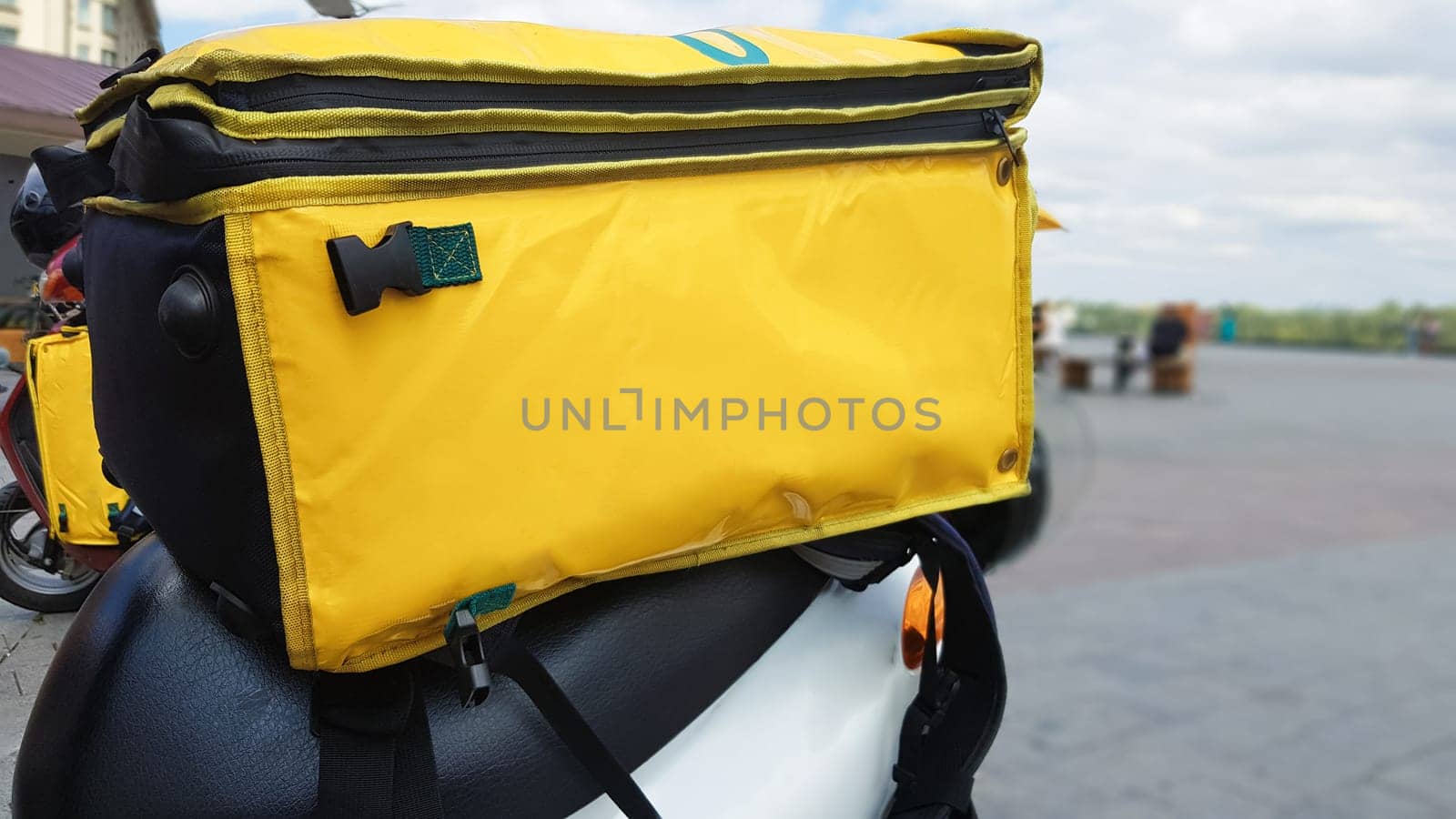 Delivery courier motor scooter with yellow backpack. A courier on a scooter is waiting for an order. Fast delivery of goods to customers from the restaurant and store. Copy space on the bag