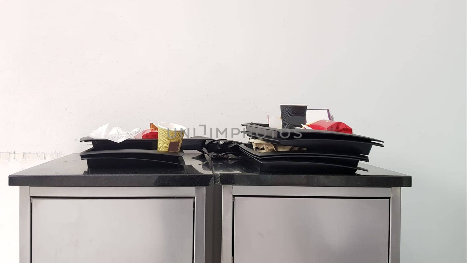 The concept of cleanliness and cleaning rules. At the exit of the fast food trash can with trays. Cleanliness and care for the environment. Tin trash can in cafes and self-service restaurants