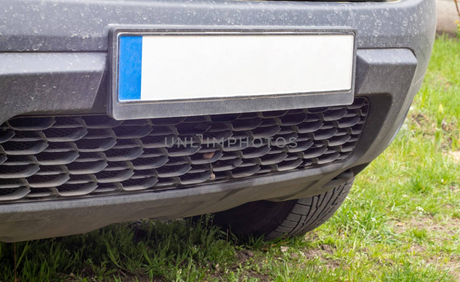 Car number without letters and numbers on the car bumper. Blank white license plate in front of the car, all logos removed, close up. The front rectangular license plate of a vehicle on the street