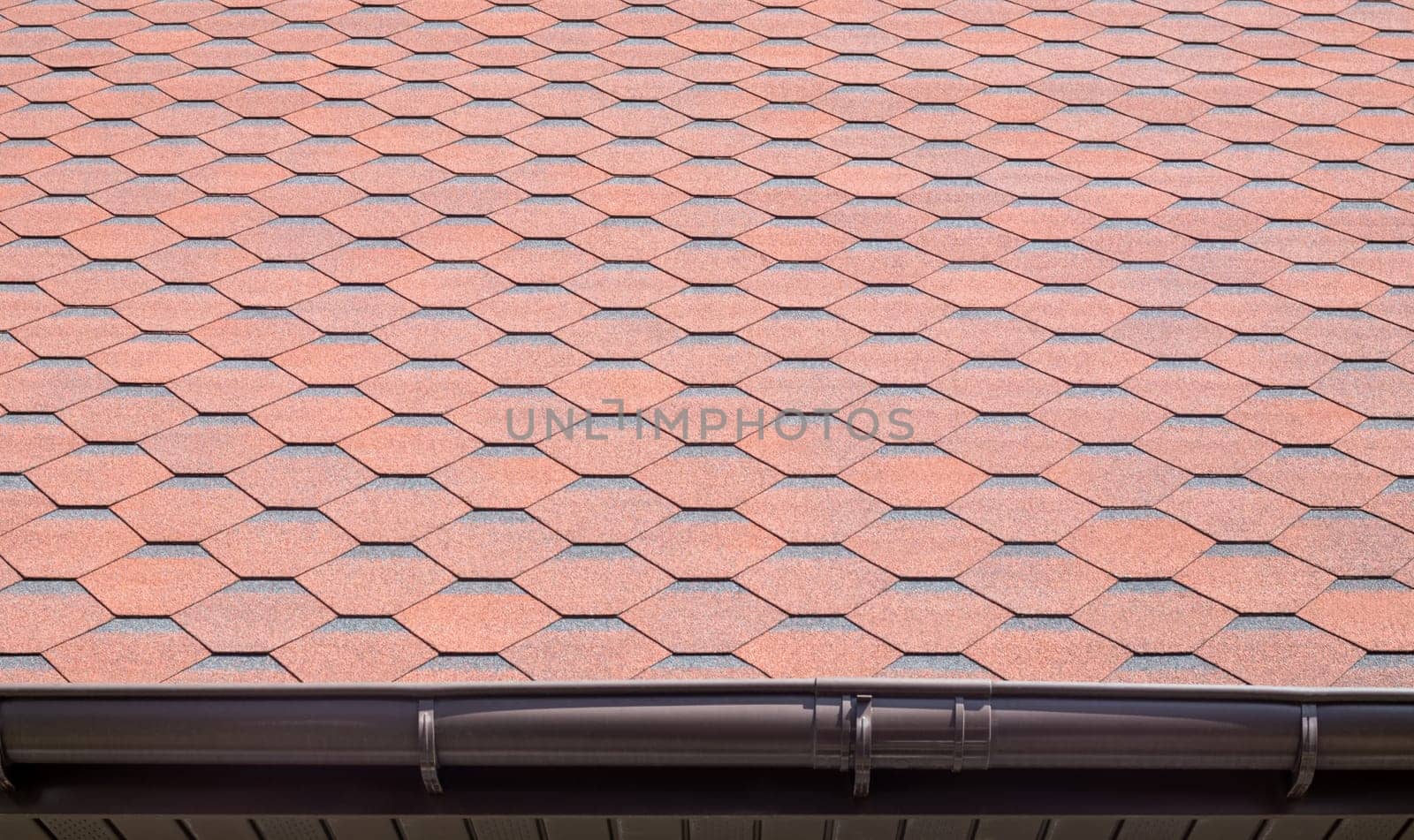 New roof with red shingles. Tiles on the roof of the house. Use to advertise roof fabrication and maintenance. Spotted texture. Affordable roofing. High quality photo with copy space