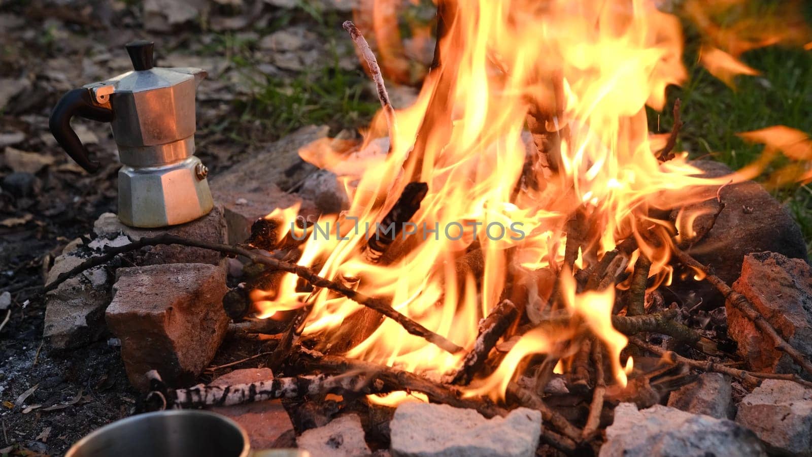 Bonfire burning in tourist camp in mountains. Beautiful campfire, burning wood in summer evening. Active lifestyle, traveling, hiking and camping concept. Campfire burning in slow motion.