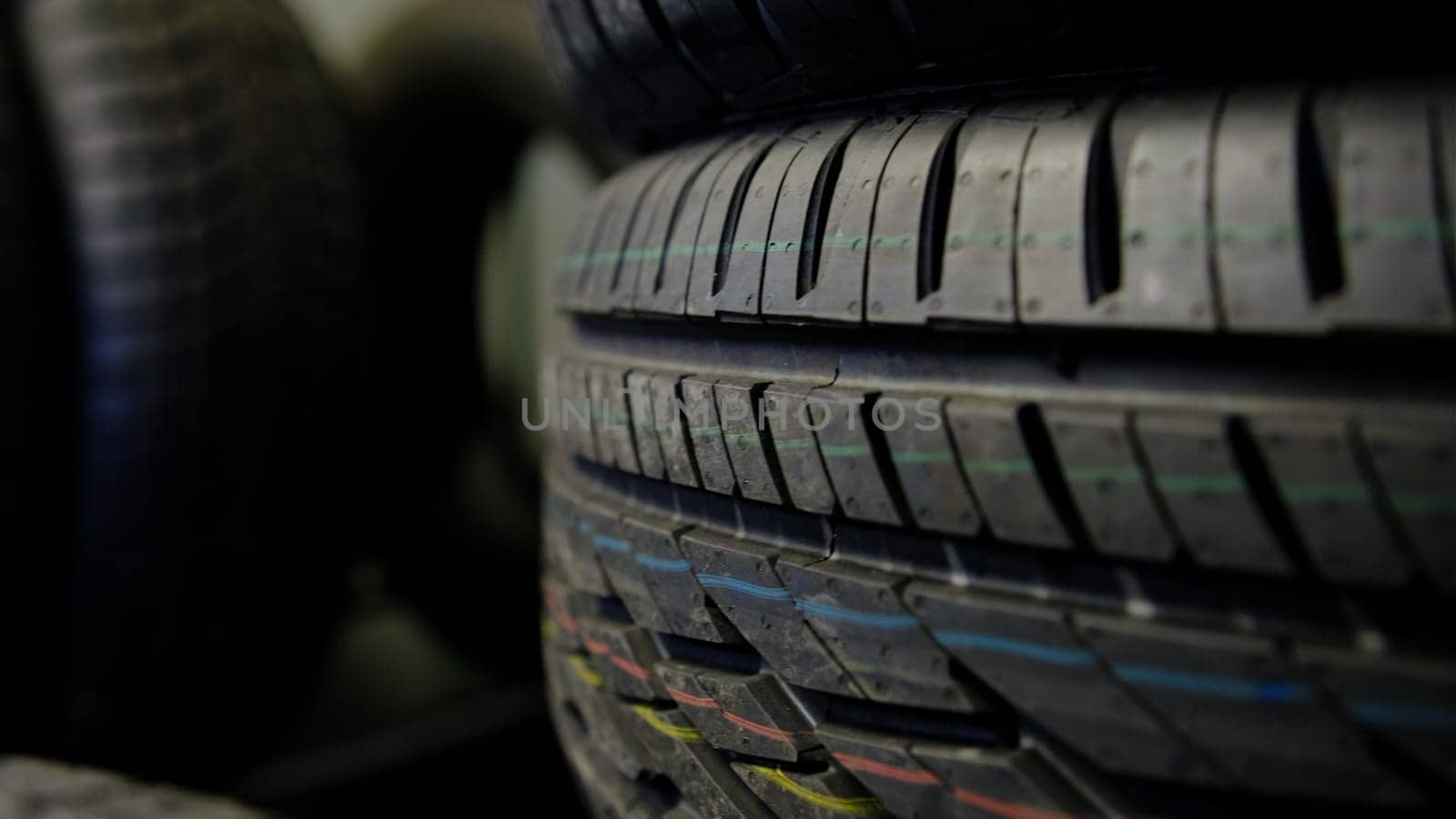 Summer tires changing to winter tires by side moving on a shop stands with dark black backgound.