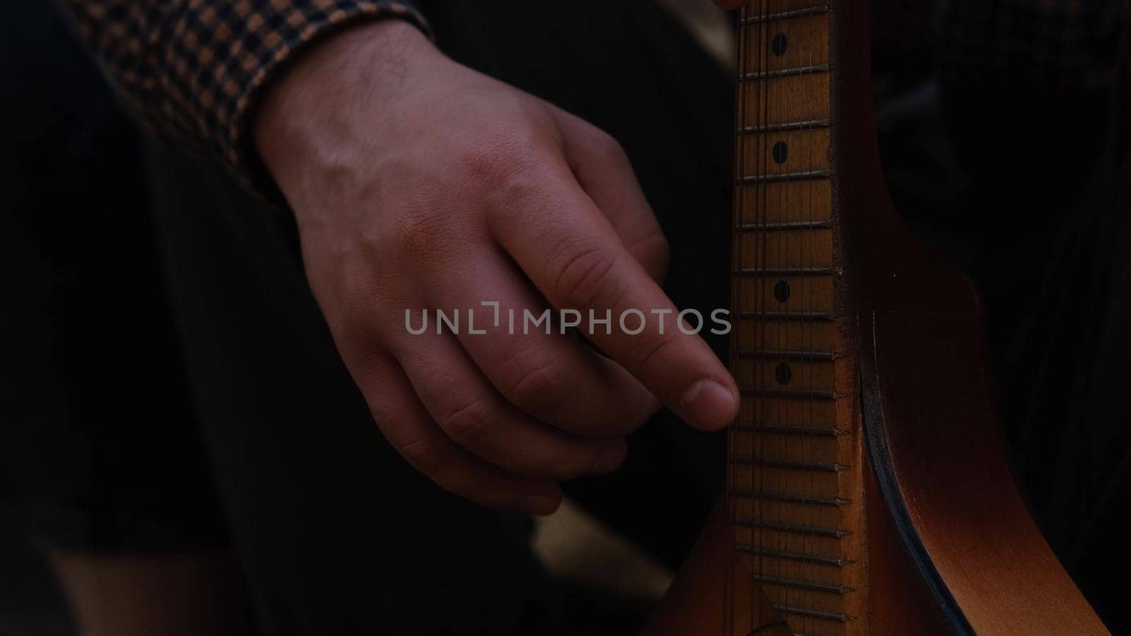 Hands of an adult man playing an acoustic guitar on the street, in a park close-up, selective focus. A man is playing an old acoustic guitar on the street. A street musician. Composer.Spanish guitar
