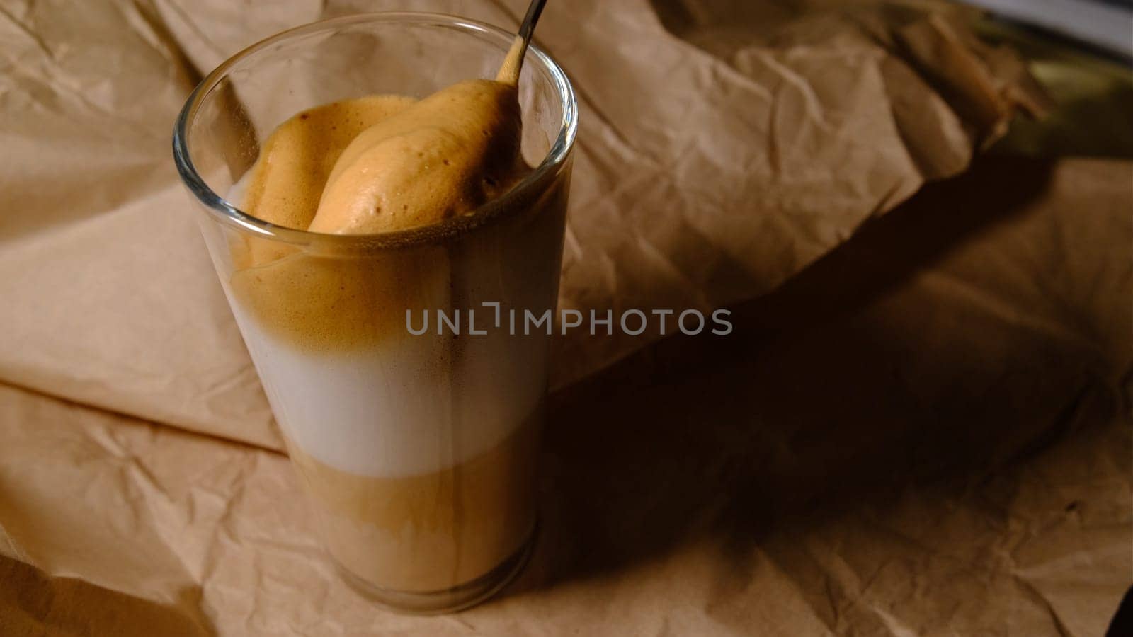 Beautiful composition - hot coffe latte cappucino in a transparent glass. Mixing by spoon 4K 400mb s