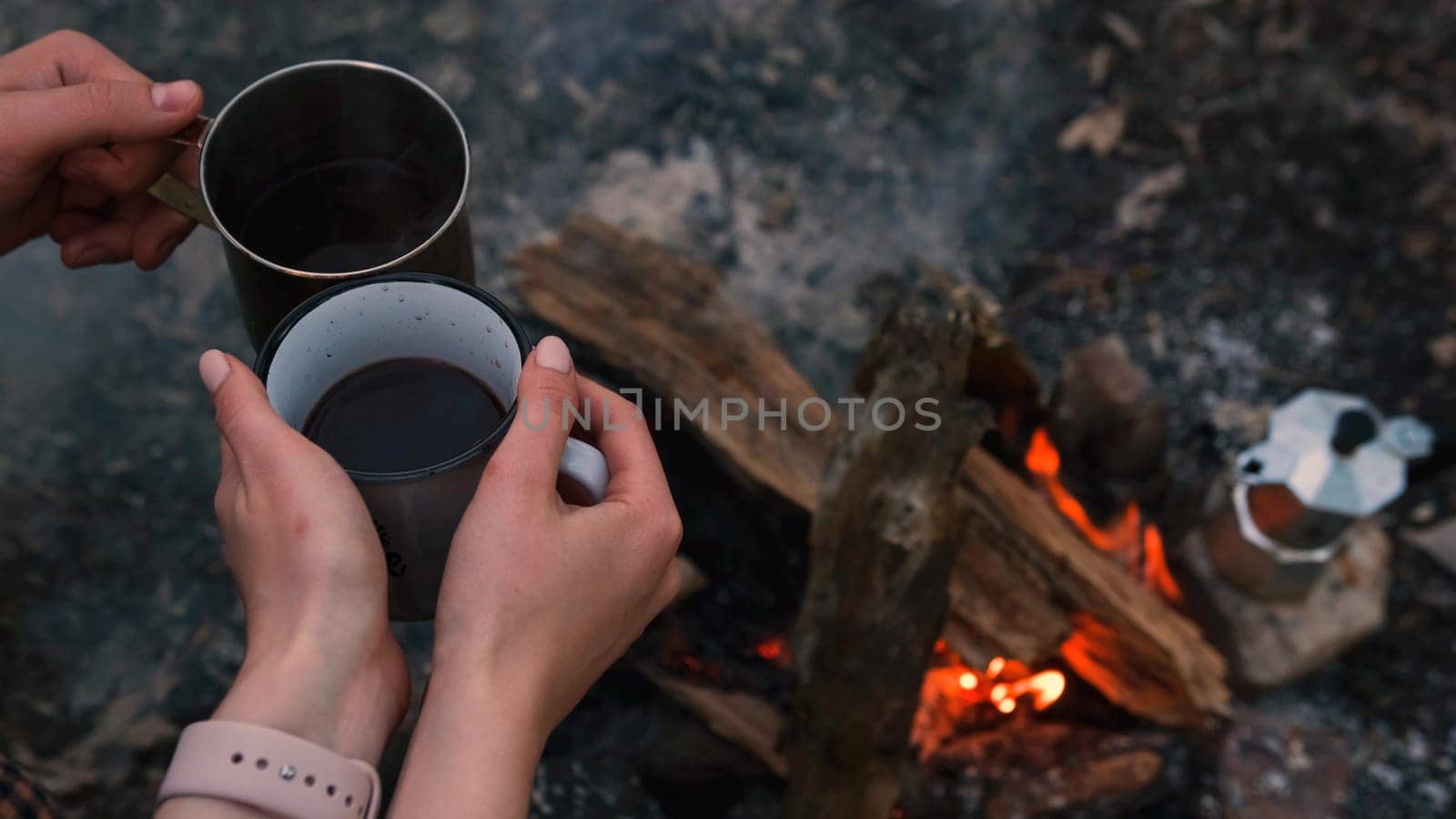 Couple in love Campsite With Fire Pit and Two Tin Cups with hot tea, coffee. Burning Campfire.