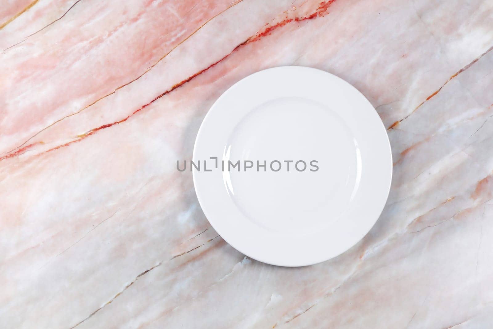 A dinner plate on a pink white and grey marble surface