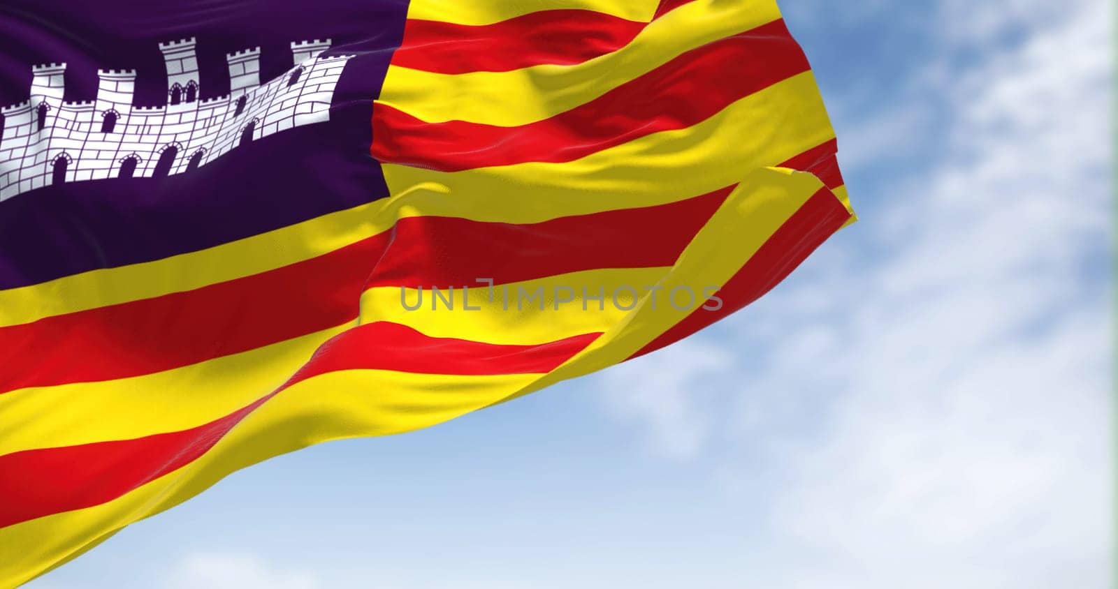 Balearic Islands flag waving in the wind on a clear day. The Balearic Islands are a Spanish archipelago in the Balearic Sea, near the eastern coast of the Iberian Peninsula