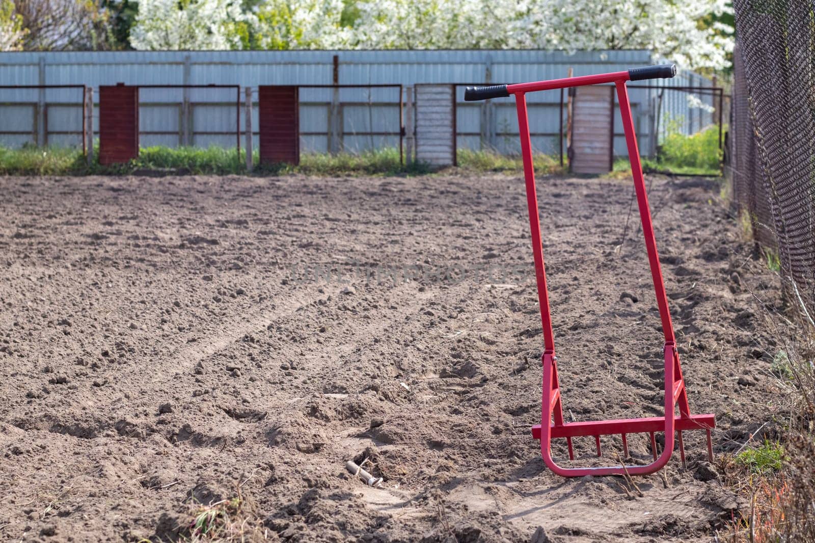 Red shovel in the form of a fork in the garden. Miracle shovel, handy tool. Manual cultivator. The cultivator is an effective tool for tillage. Bed loosening. Sustainable agricultural tools