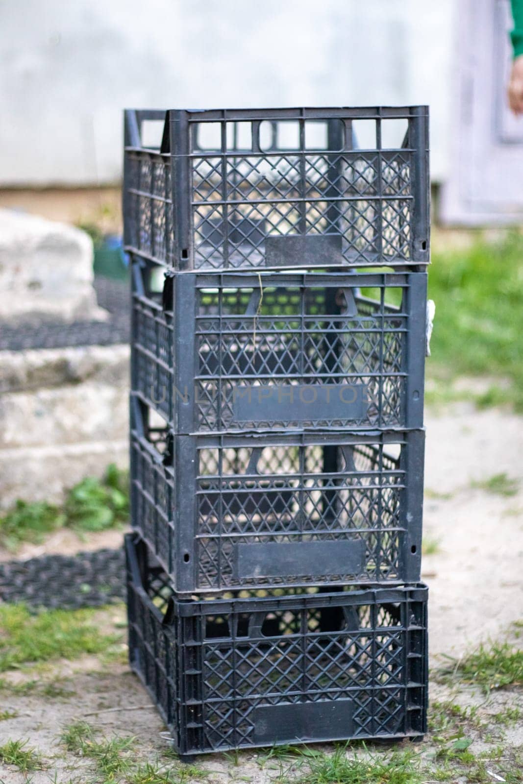 Plastic empty black boxes stacked together for plants or harvest. On a sunny day in early spring. Gardening concept. Household crop collection and storage boxes standing in the backyard