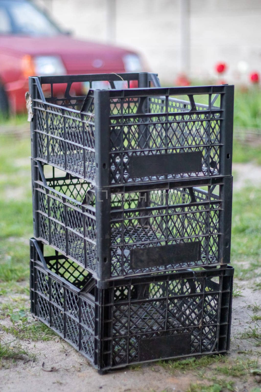 Plastic empty black boxes stacked together for plants or harvest. On a sunny day in early spring. Gardening concept. Household crop collection and storage boxes standing in the backyard