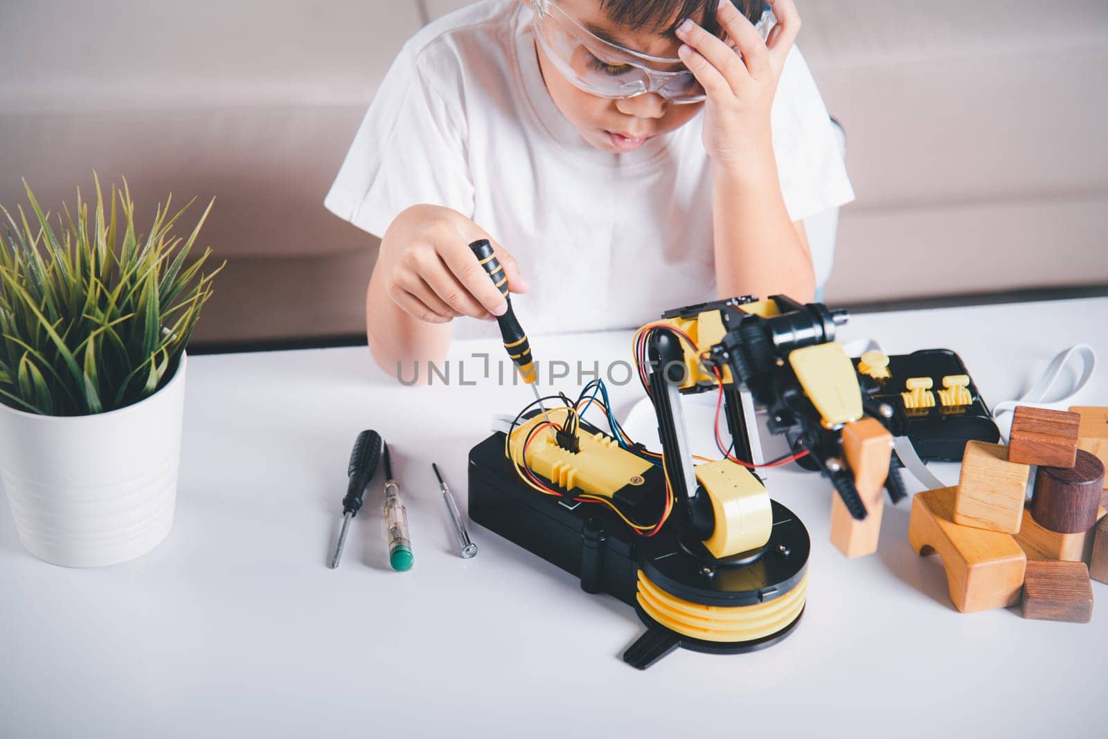 Child learning repairing getting lesson control robot arm, Happy Asian little kid boy using screwdriver to fixes screws robotic machine arm in home workshop, Technology future science education concept