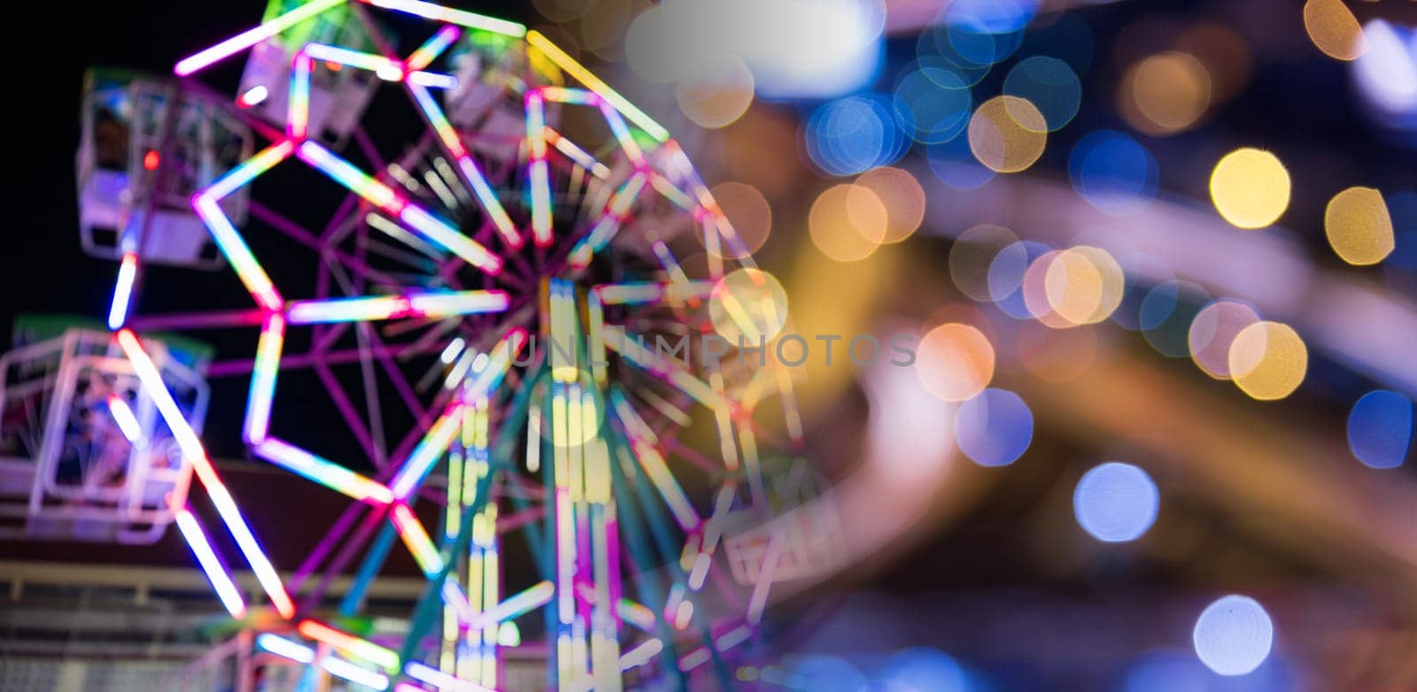 Blurry rollercoaster in bokeh, Ferris wheel at night of colorful with outdoor, Defocused (blurred) and blur image of Amusement park, The annual temple event has activities. Image out of focus