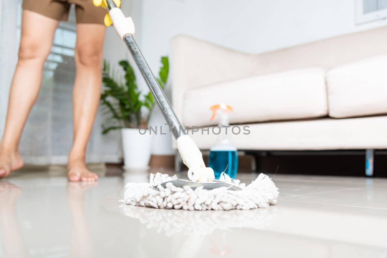 Asian woman washes the floor with a mop and rag indoors, housewife washing floor mopping at home in living room cleaning her home, Professional housekeeping job house cleanup concept