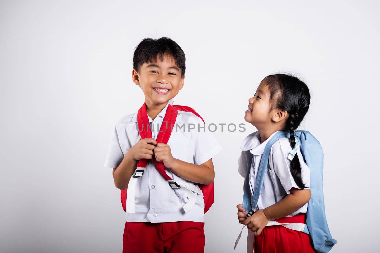 Two Asian student kid girl boy schoolchildren brother sister smile happy wear student thai uniform red pants skirt in studio shot isolated on white background, Portrait little children girl preschool