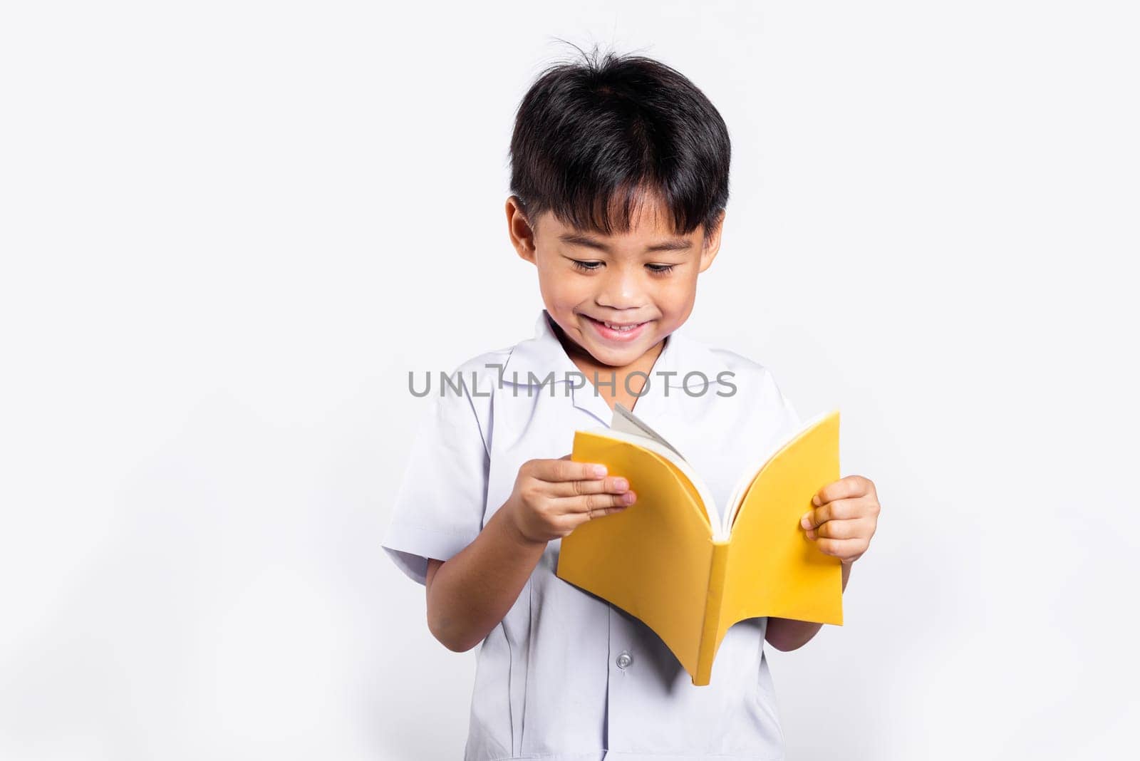 Asian toddler smile happy wearing student thai uniform red pants standing holding and reading a book in studio shot isolated on white background, Portrait little children boy preschool, Back to school