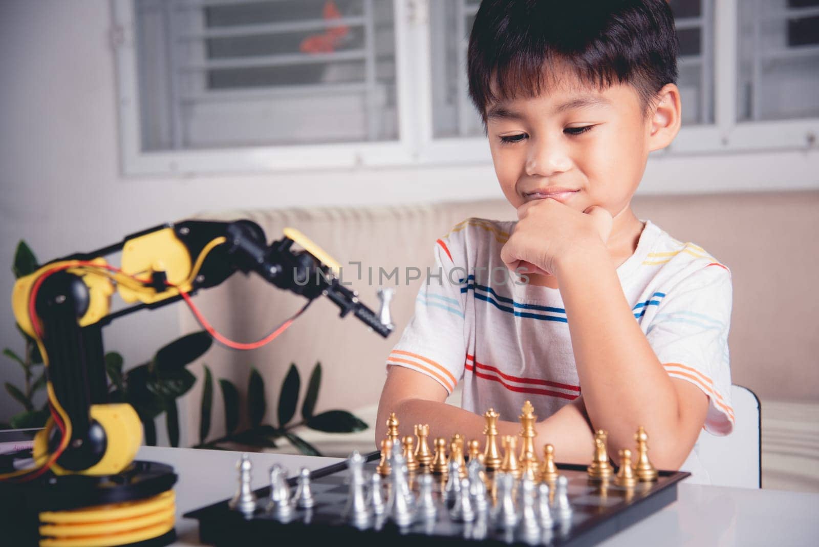 Asian little boy thinking and wait robot arm playing chess, STEM education E-learning, Funny children learning successful getting a lesson control robot arm game, Technology science education concept