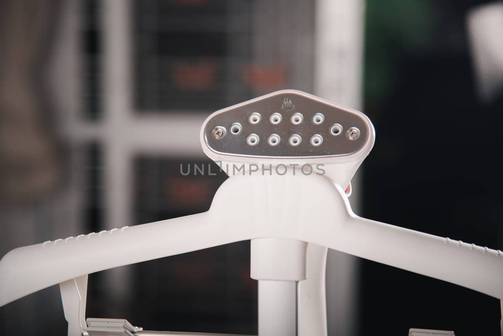 Close up of electric hand steam generator while it's hot on the ironing board place for clothes at house, Household & home equipment for housework, concept of linen care