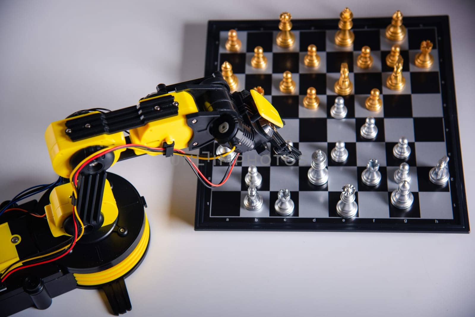 Closeup yellow robot arm playing move chess on chessboard, STEM education E-learning, Technology science robot education concept