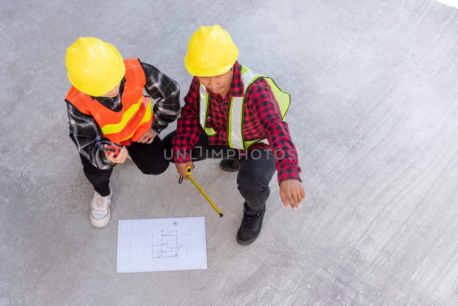 Architect and client discuss help create plan with blueprint of the building at construction site floor. Asian engineer foreman worker man and woman meeting talking on drawing paper project, top view