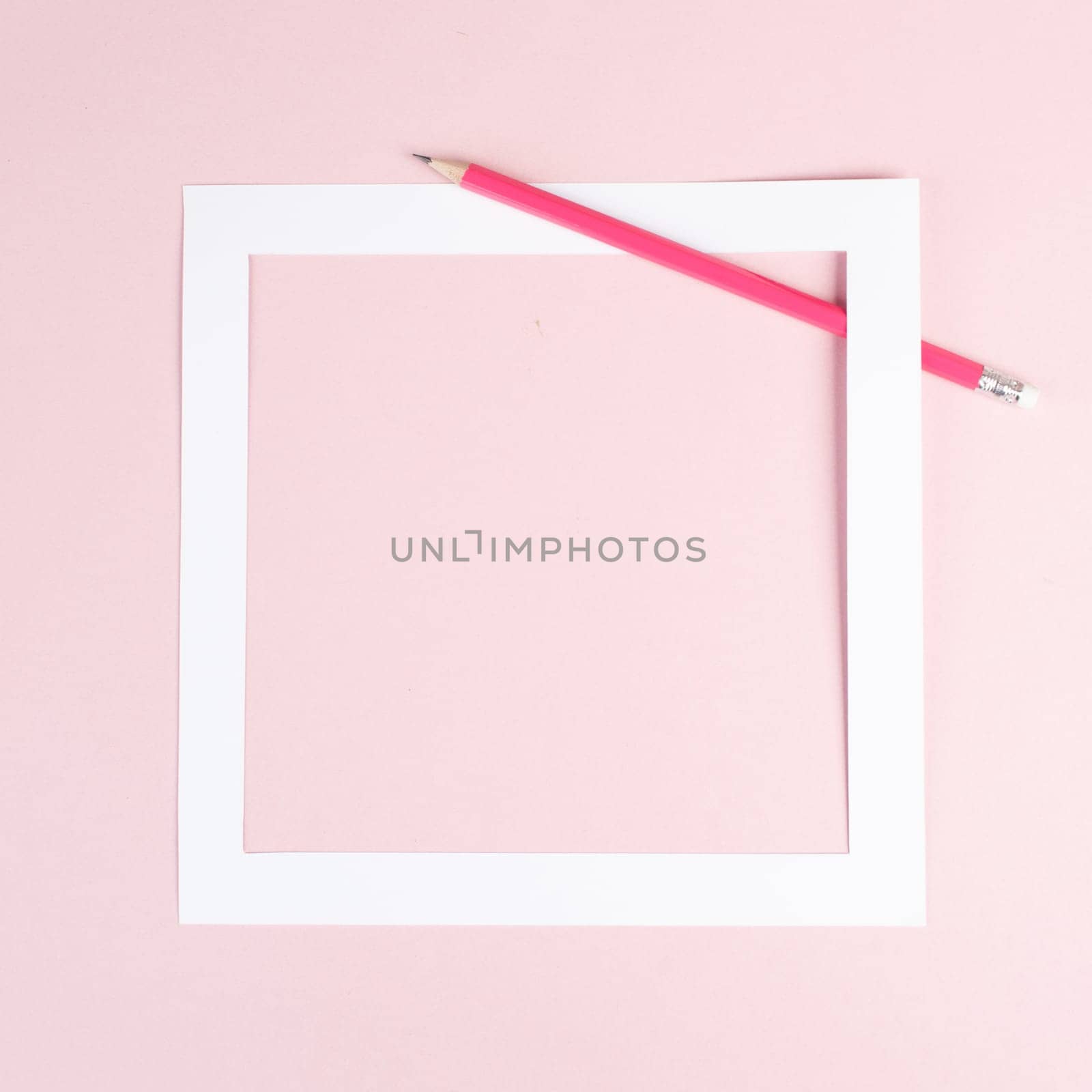 Pencil on a pink paper background, white frame with copy space for text, minimalism, creative and business concept, pastel colored