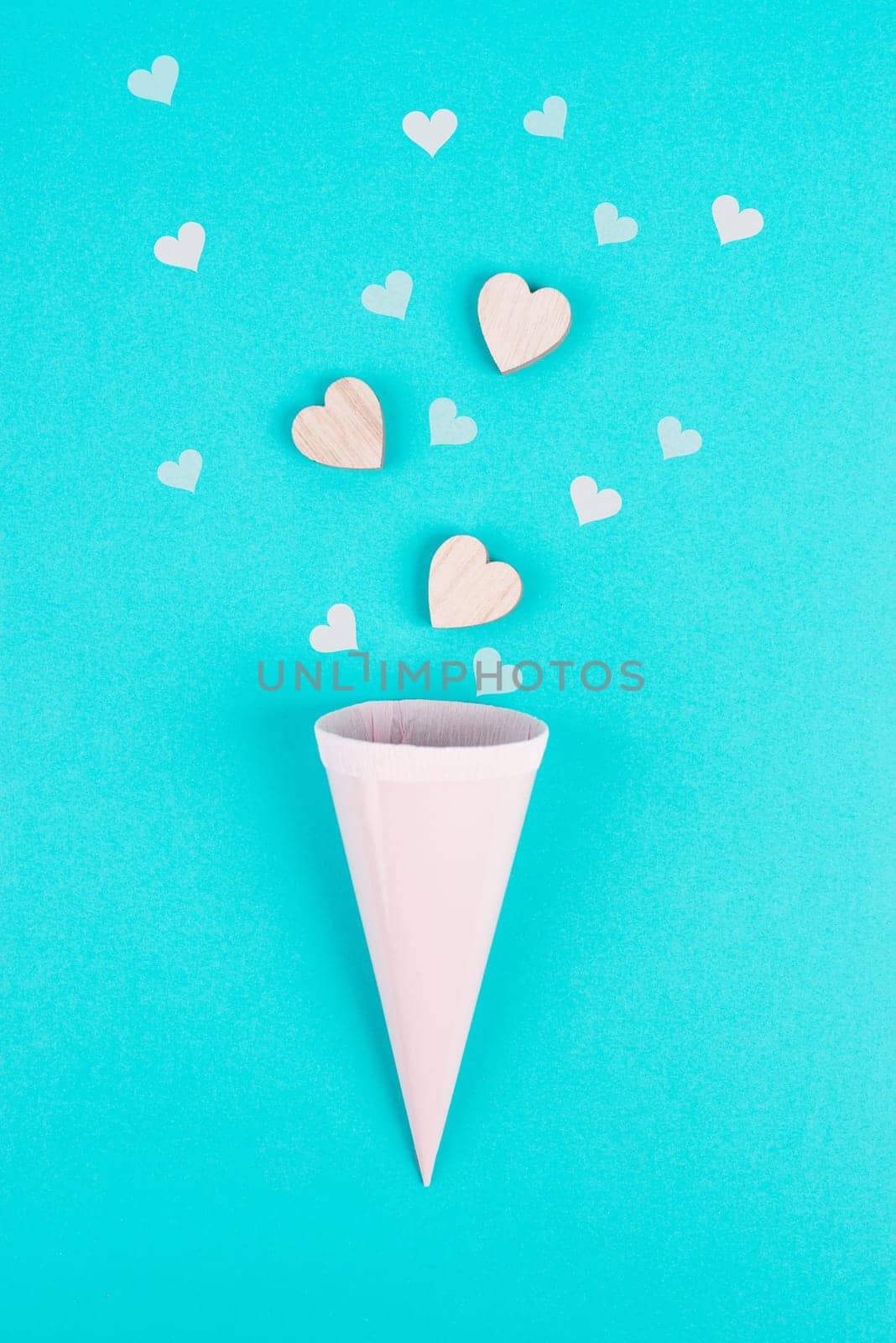 Cone with rose colored hearts, blue background, birthday and valentines day greeting card, spreading love, positive emotion, flat lay