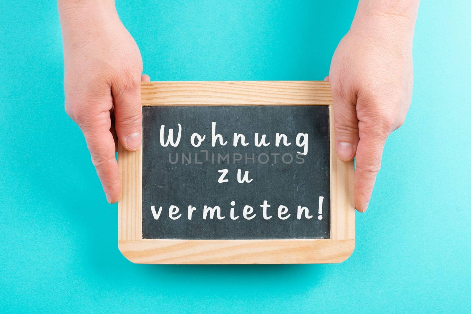 Holding a chalkboard in the hands, apartment for rent is standing in german language on the sign, moving to a new home, real estate
