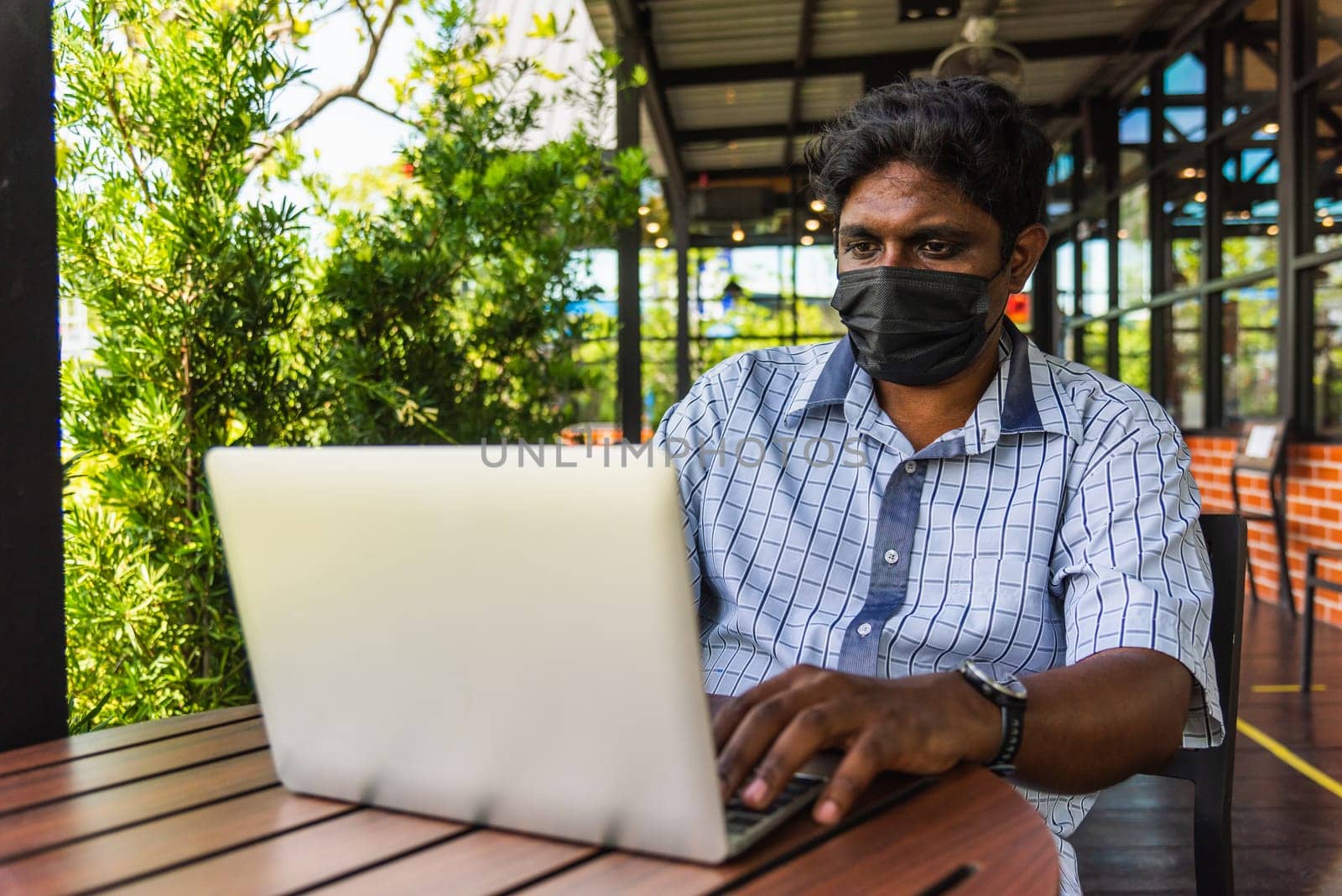 Happy Asian hand black man person sitting working with laptop computer, device technology and connecting networking online at the coffee cafe shop