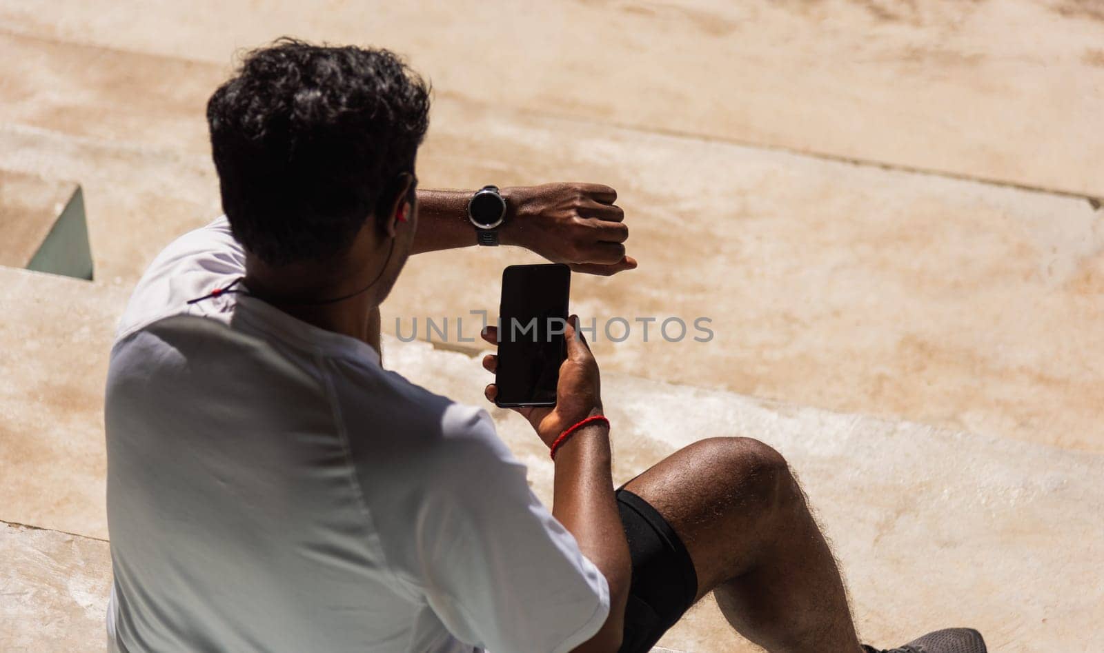 Close up Asian young athlete sport runner black man wear modern time smart watch and sync to a smartphone check running result after a training run at the outdoor, healthy exercise workout technology