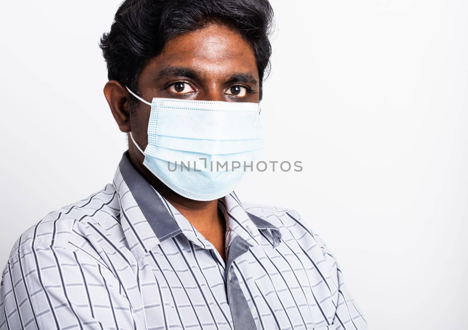 Closeup Asian handsome black man wearing surgical hygienic protective cloth face mask against coronavirus and stand crossed arm, studio shot isolated white background, COVID-19 medical concept