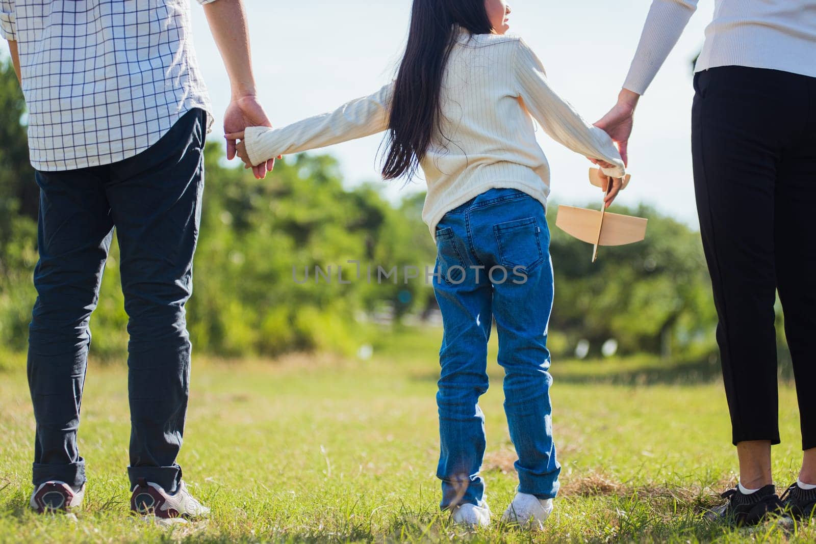 Happy Asian young family father, mother and child little girl having fun and enjoying outdoor walking down the road outside together in green nature park on a sunny summer day