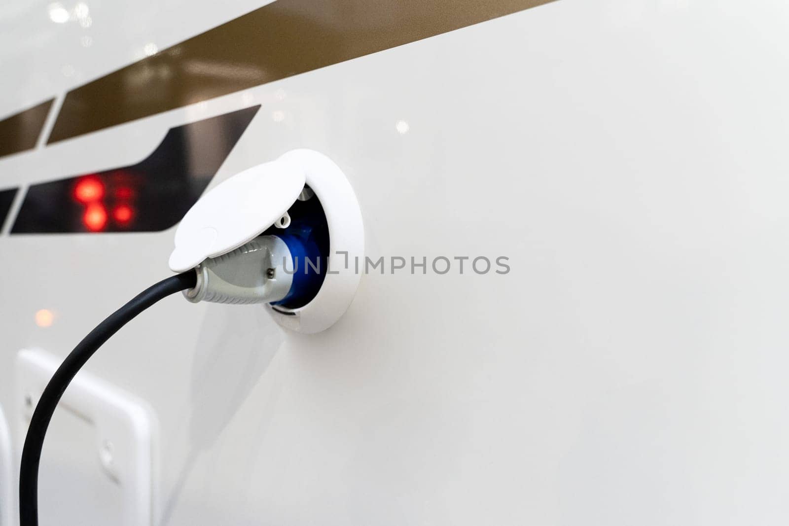 perspective view closeup of motorhome electricity outlet plug attached to stationary white RV travel campervan