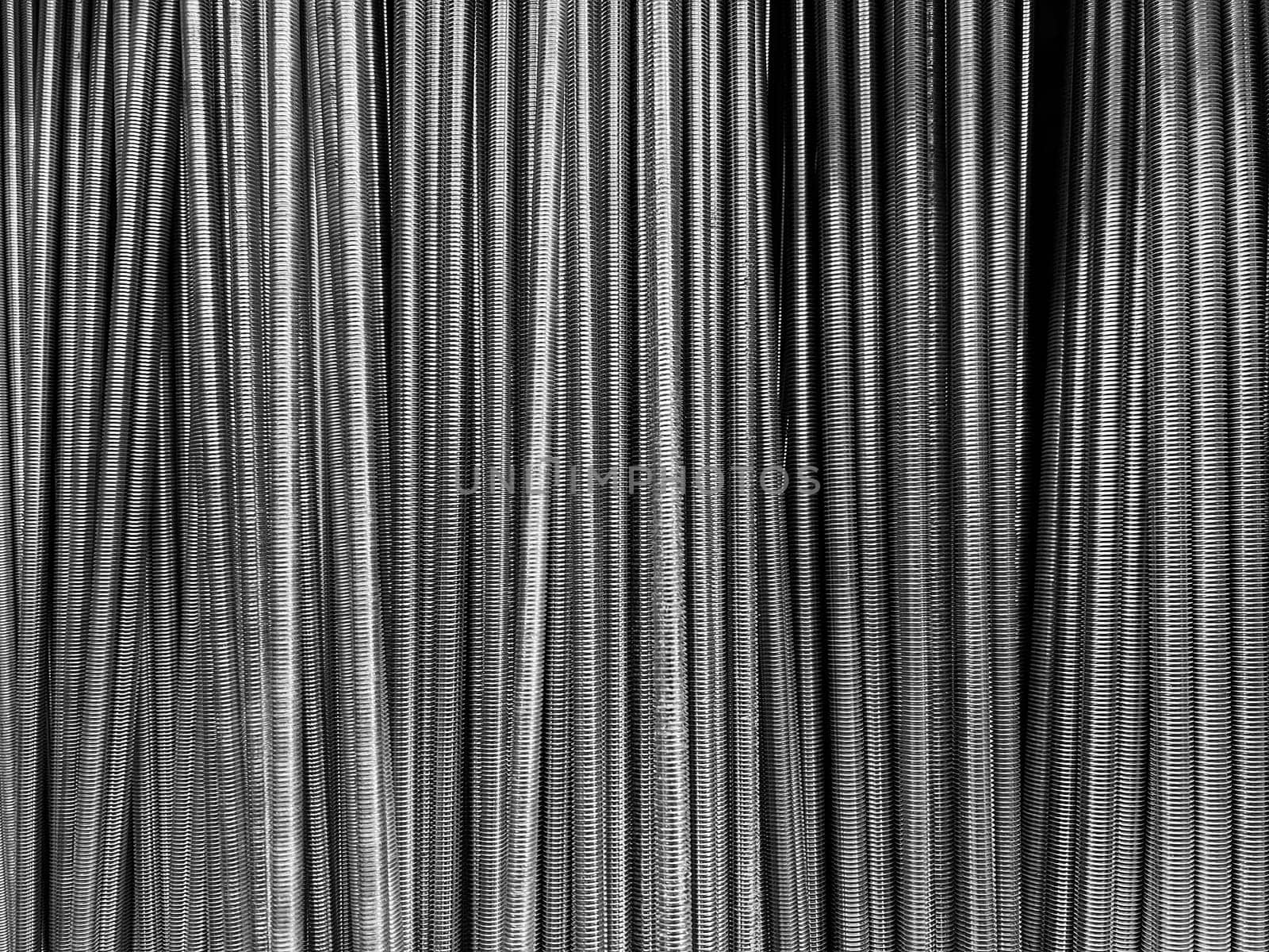 front view closeup of many long threaded steel bars for industrial use