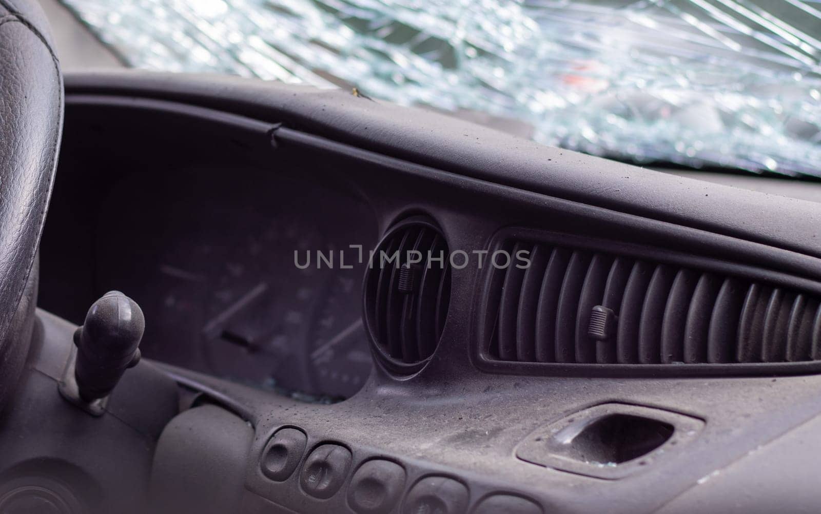 Close-up of the steering wheel of a car after an accident. The driver's airbags did not deploy. Soft focus. Broken windshield with steering wheel. Vehicle interior. Black dashboard and steering wheel