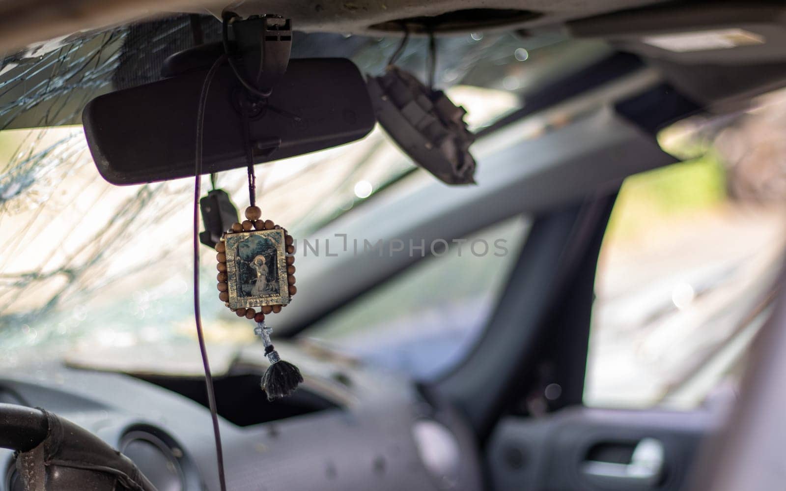 Broken car windshield from a bullet, inside view. Damaged glass with traces of an oncoming stone on the road. Interior view of the car. Translation: Seraphim of Sarov the Wonderworker