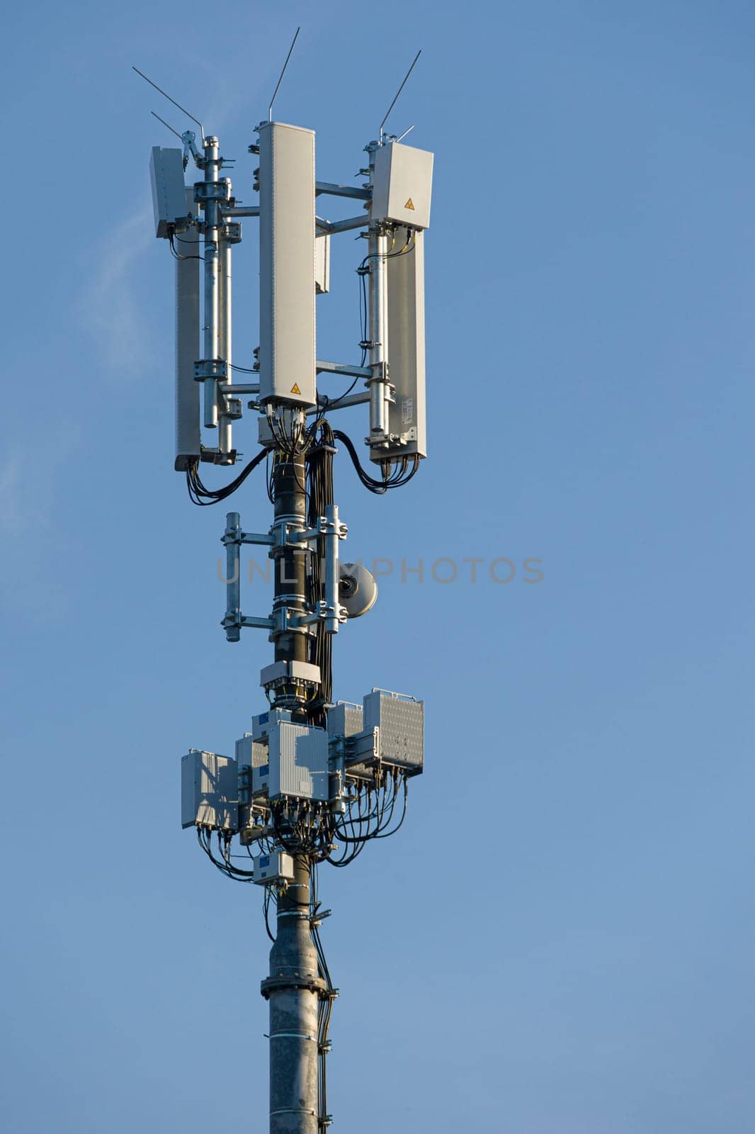 antenna mast with defferent antennas for mobile radio communications in front of blue sky