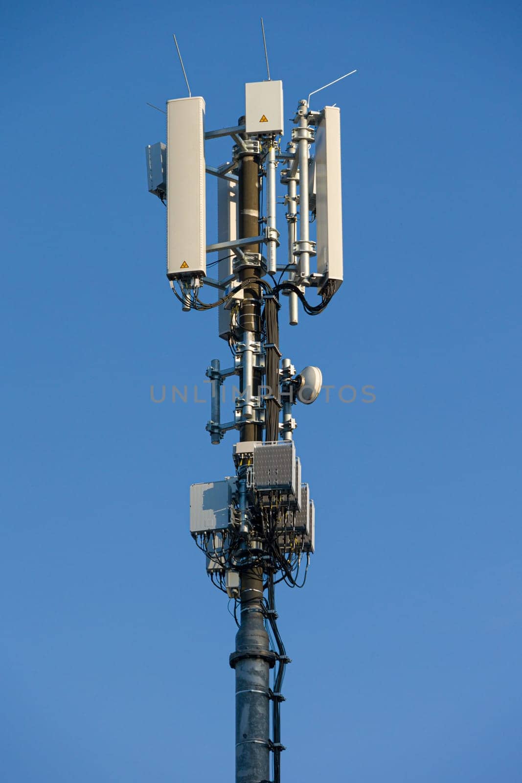 antenna mast with defferent antennas for mobile radio communications in front of blue sky