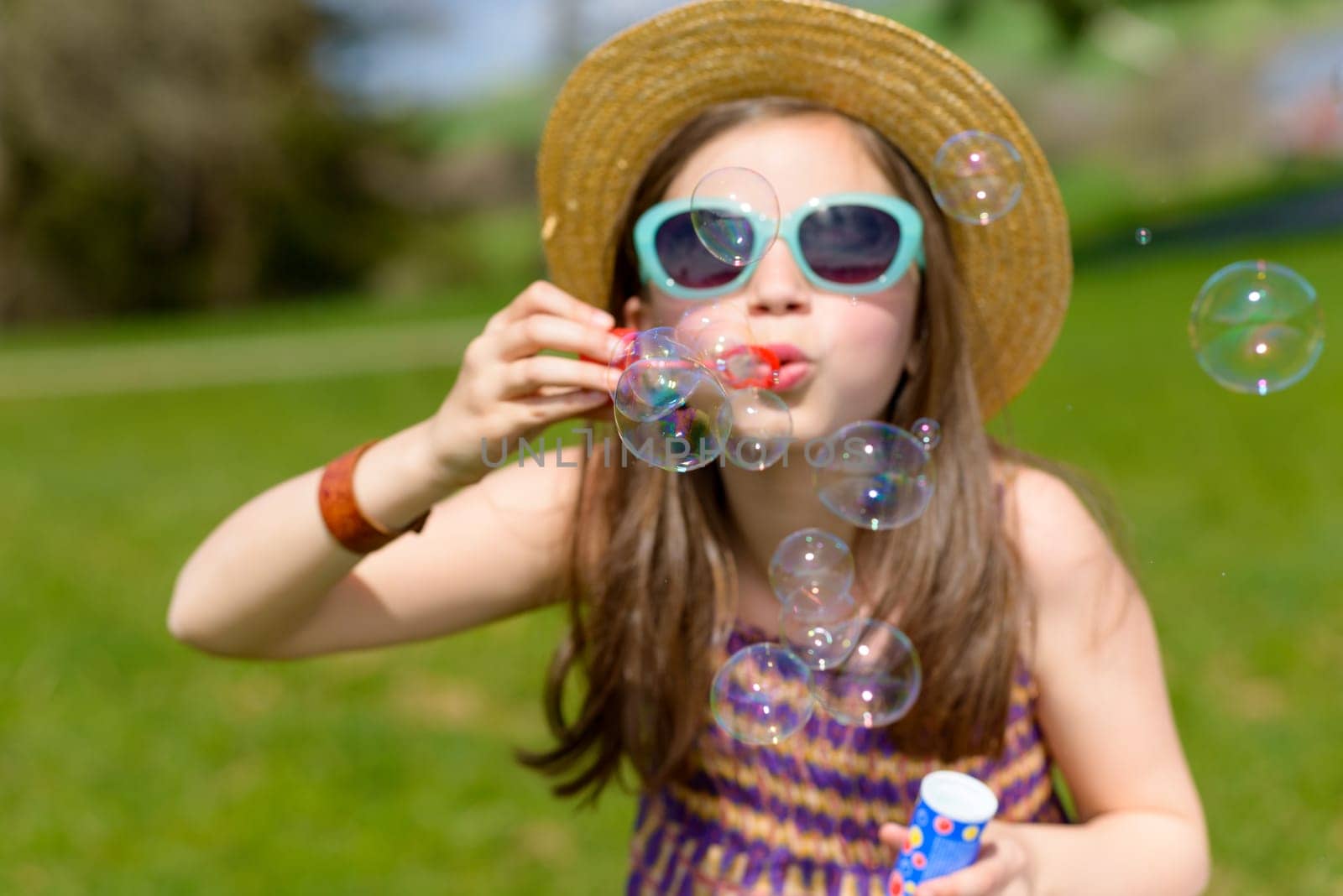 a little girl making soap bubbles in nature